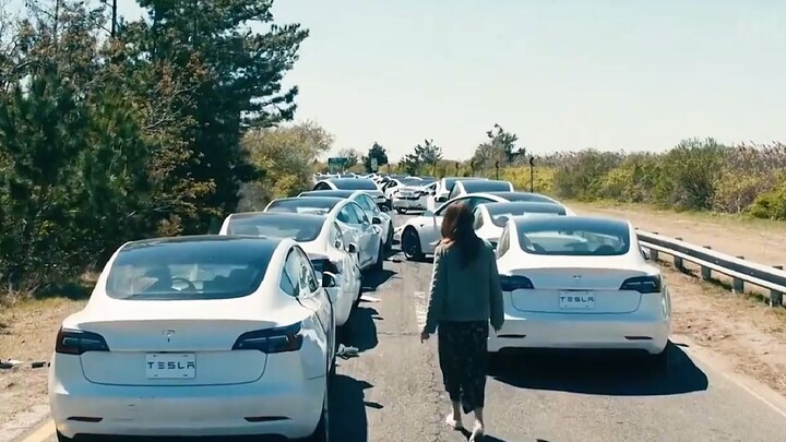 女人正在路上查看前面撞在一起的汽车，下一秒竟有无数辆汽车向她撞来