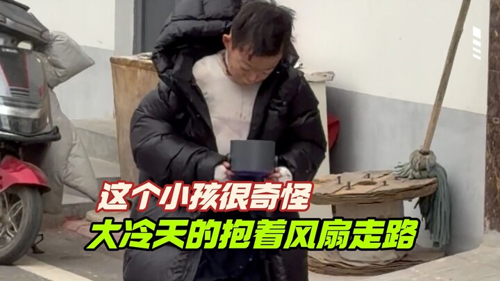 This kid is really strange—on a freezing day, they’re walking around holding a fan!