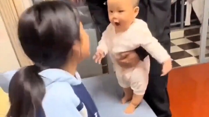 The baby only dares to tussle with his older sister in Dad’s arms—so funny!