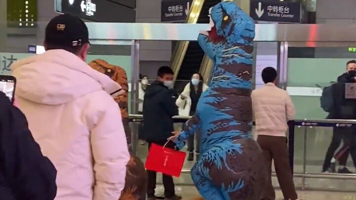 Ayah dan anak dijemput di bandara dengan pakaian dinosaurus, sangat menyenangkan menarik orang untuk