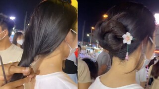 Seorang kakek yang menjual jepit rambut di pasar malam mengajari para gadis cara menggunakan jepit r