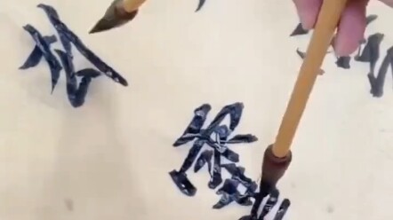 Người đàn ông một tay cầm hai cây bút, đồng thời viết hai chữ khác nhau.