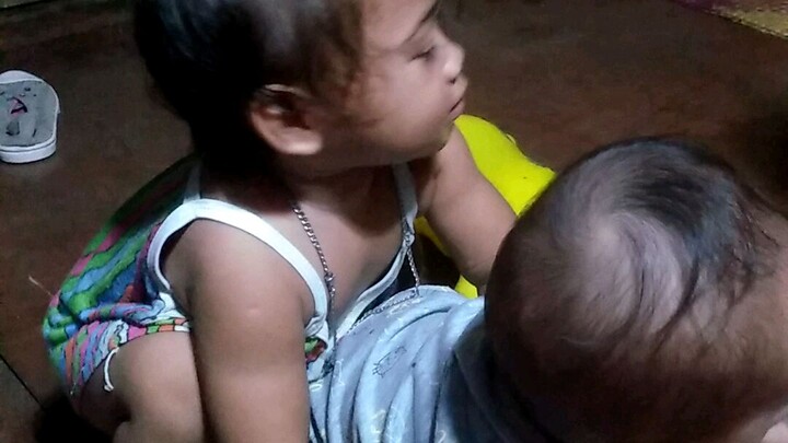 baby sister trying to carry her sister