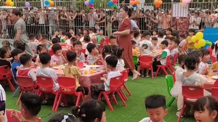 Kindergarten kids sit around a table enjoying a grand feast to celebrate Children’s Day in a unique 
