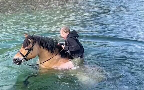 A woman rides a horse across a deep river; the water is crystal clear and profoundly deep. Unexpecte