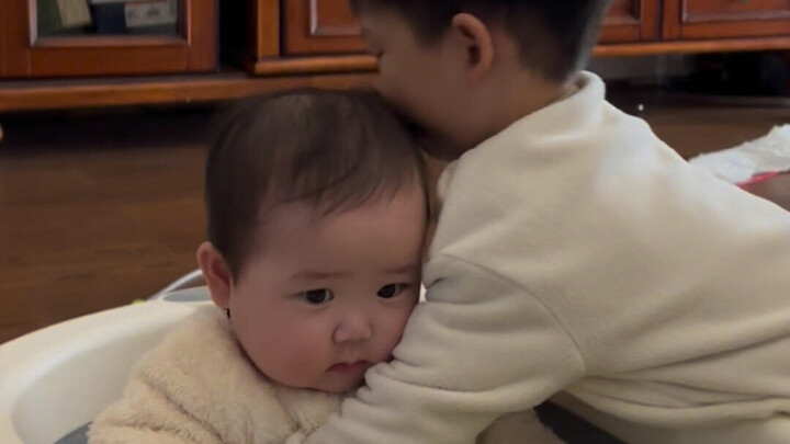 Big brother wants to hug his little sister again, but her head is even bigger than his!