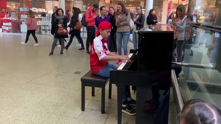 Asian boy playing "Queen - We Are The Champions" at St. Pancras Station in London