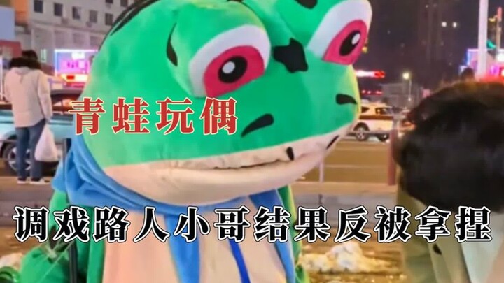 The frog doll wears an utterly innocent, goofy expression; it teases a passerby but ends up getting 