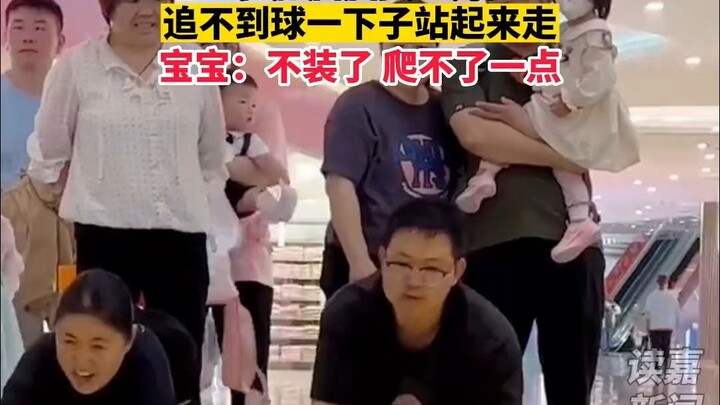 The baby "cheats" in the crawling competition. When he can't catch the ball, he stands up and walks.