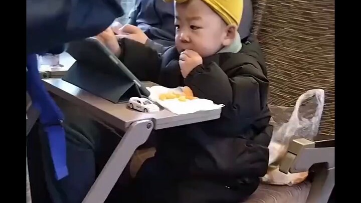 Bocah laki-laki yang tenang menikmati jeruk kecil di dalam kereta cepat benar‑benar menghangatkan ha