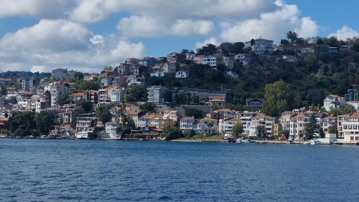 Scenic boat ride passing beautiful hillside houses and a coastal mosque along the Bosphorus.