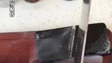 Man chops meat and slices his phone in half, causing it to smoke.
