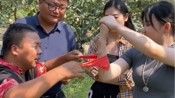 A middle-aged man shows off an amazing trick for a beautiful woman: a silk scarf passes through his 