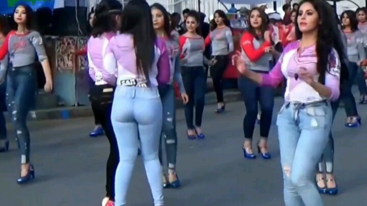 A large group of foreign girls in jeans are dancing on the street...