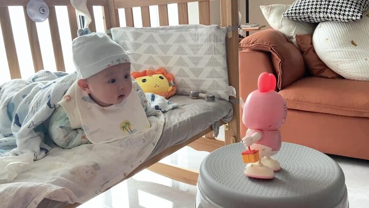 The human baby is stunned by the new toy, their face brimming with curiosity. Netizens: Such an ador