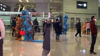 الأب والابن يرتديان زي الديناصورات في المطار لاستقبال الأم، بينما الأم تغادر وكأنها مجرد مارة غير مب