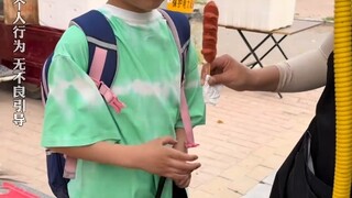 妈妈来接自己女儿放学，发现有男同学请客吃烤肠背书包