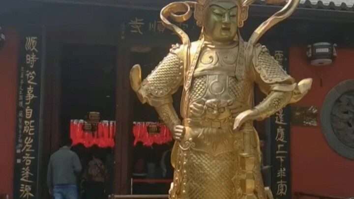 A woman kneels in front of a God of Wealth temple to scratch “scratch-off” lottery tickets; netizens