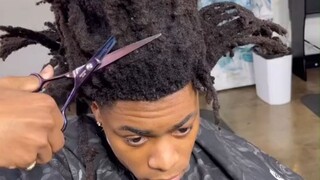 The barber trims the customer's dreadlocks and adds a "knife-cut" hairline after the cut