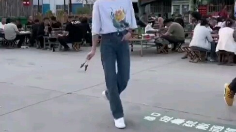 Zibo, Shandong: A young woman effortlessly performs a one-handed backflip while holding a skewer of 