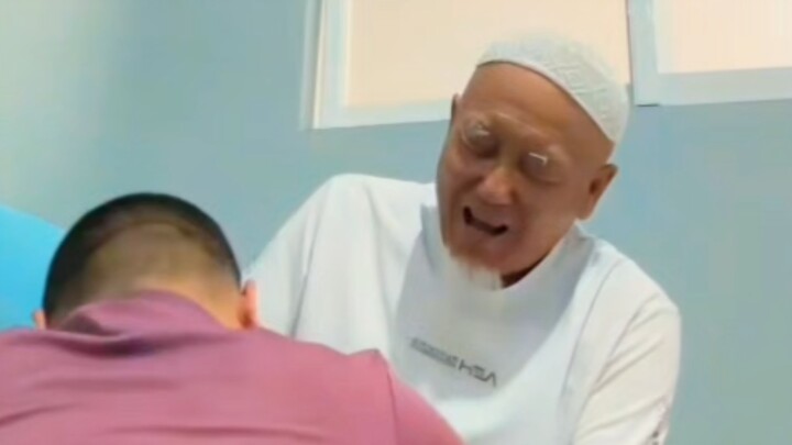 An old man with a white beard receiving a massage
