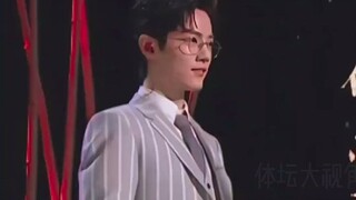 When the teacher mentioned a tie, he pulled it with his hand. When the teacher mentioned shoes, he l