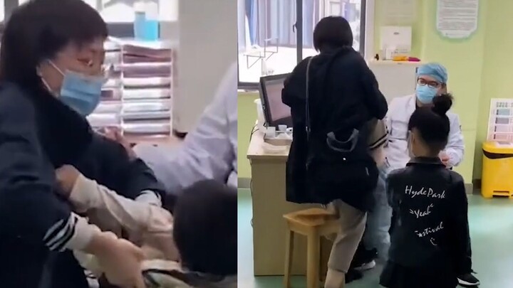 Ibu kesulitan menahan anak saat disuntik, lalu seorang ayah yang lewat membantu menahannya—si anak d