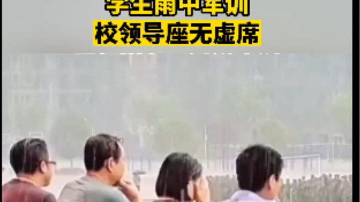 Students endure rain during military training while school leaders sit in the stands, staying with t