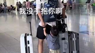 Uncle is holding luggage in both hands, yet the baby keeps running after him, begging to be held!