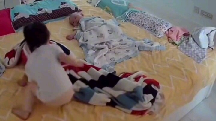 With no one else at home, the 2-year-old sister ignores her own tears to calm her 5-month-old brothe