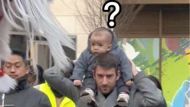 A human baby watching lion dance for the first time