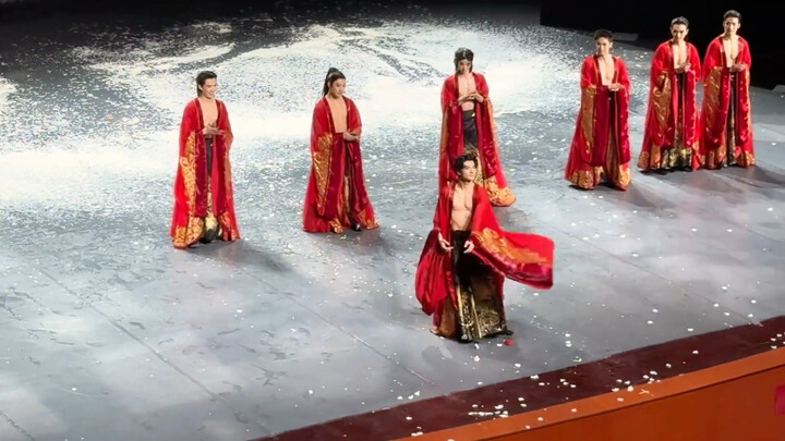 Một hàng các anh chàng mặc trang phục đỏ kim hoa đứng thẳng tắp.