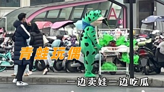 The frog doll has a kind of innocent silliness, selling dolls while casually gossiping.