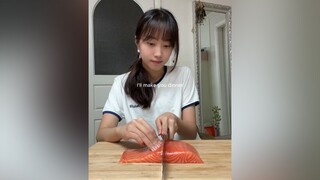 Một cô gái làm món cá hồi. Nếu bạn không hiểu, tại sao bạn lại quấn cá bằng rong biển trước?