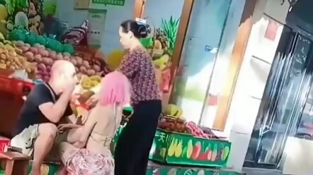 Seorang kakek botak dan seorang wanita muda bermesraan di pinggir jalan, sebuah adegan yang sulit sa
