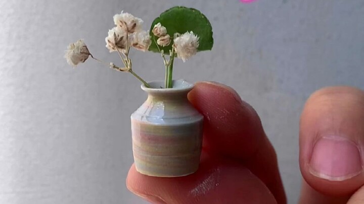 Terbuat dari tembikar mini di ujung jari, bunga kecil dalam vas keramik kecil terlihat sangat lucu d