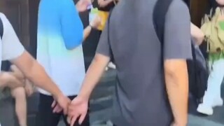 男子头也不回以为牵着的是女朋友 被牵错的大哥掩面满脸通红 一旁正在拍摄的女朋友:就这样被人牵走了