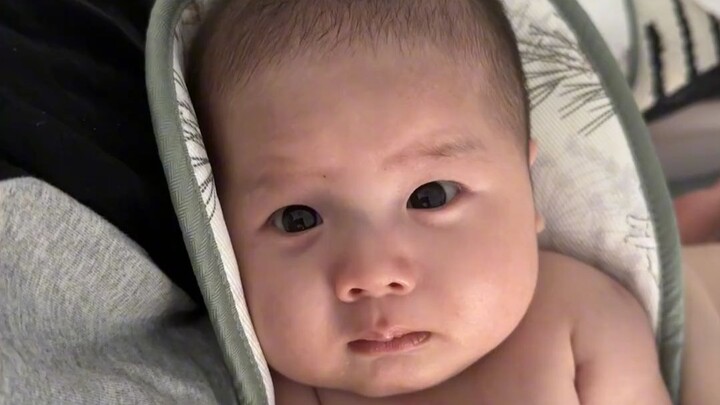 The baby was about to cry after waking up, but then realized they were in mom's arms and awkwardly h