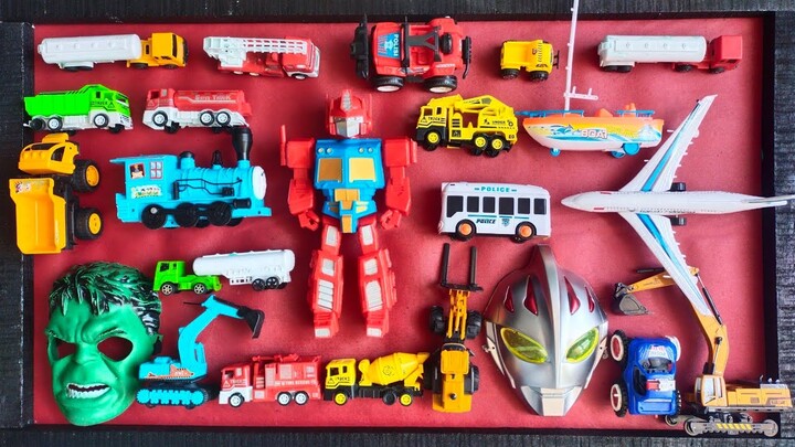 menemukan mainan mobil polisi, tank, excavator, mobil pemadam, topeng hulk, topeng ultraman, truk