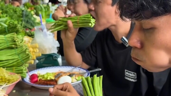 Noodle slurping at a Thai street-side stall, with an array of fresh seasonal vegetables eaten straig