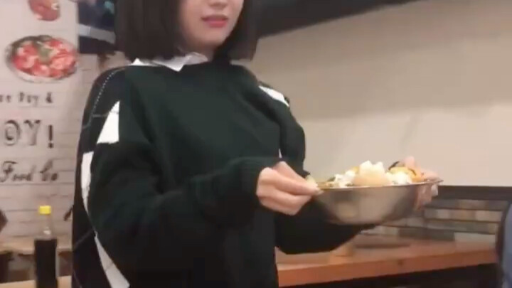 A girl carefully carrying a basin of food.