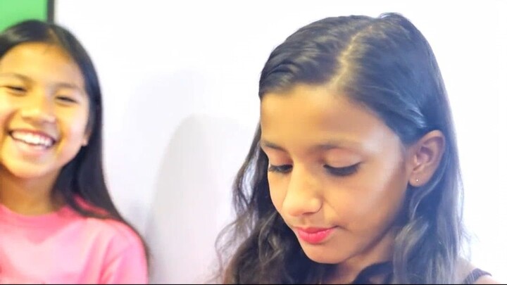 In a vibrant classroom, a girl carefully applies bright red lip