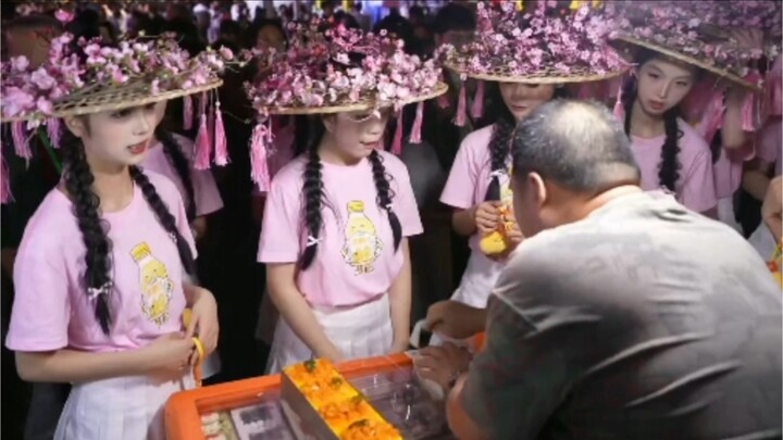 The cute girls from the Meizhou cheerleading squad are buying little cakes.