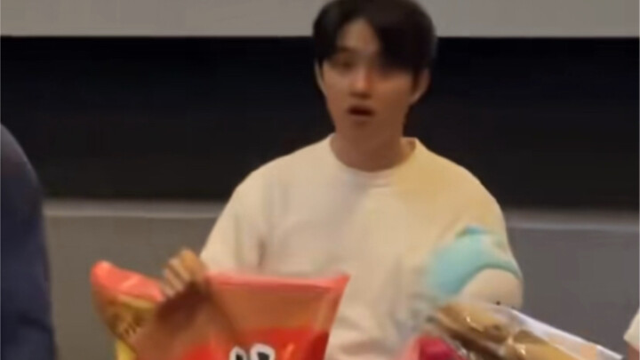 This表情 is hilarious—his whole face is just screaming, “Why is this bag of snacks so huge?”