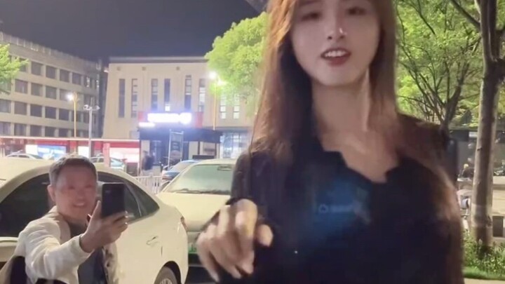 A cross-dressing man dances in front of an older gentleman.